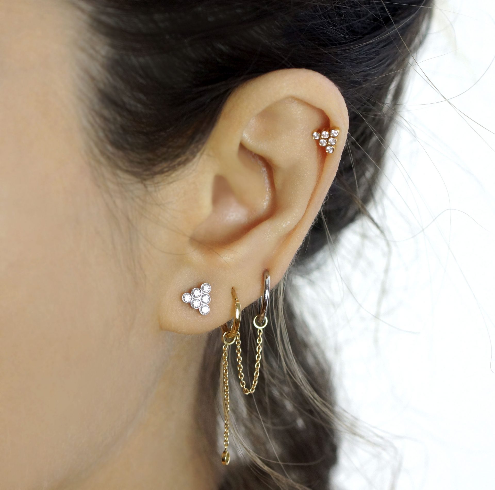 Close-up of dark-haired woman with earring stack in left ear.