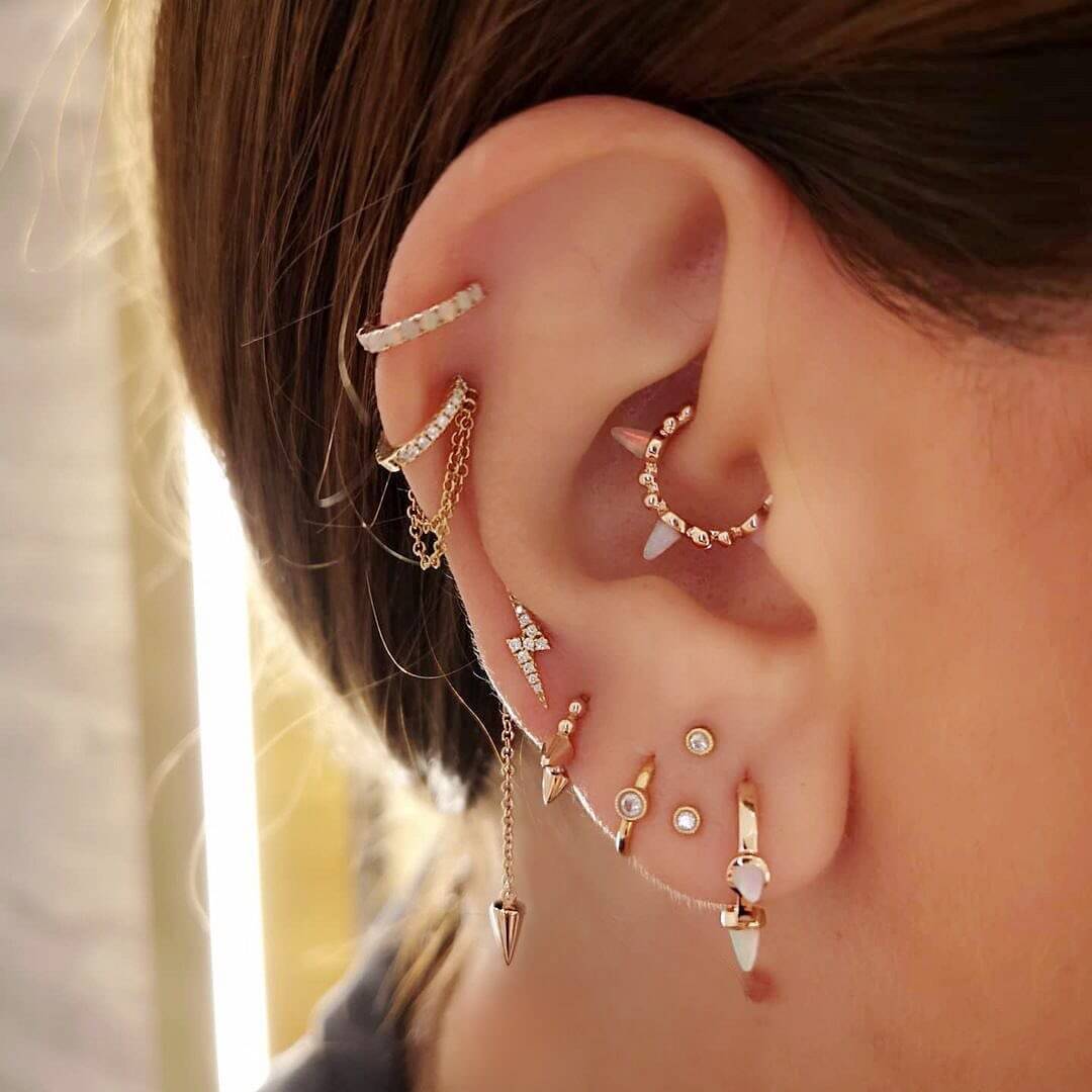 Close-up of dark-haired woman with earring stack in right ear.