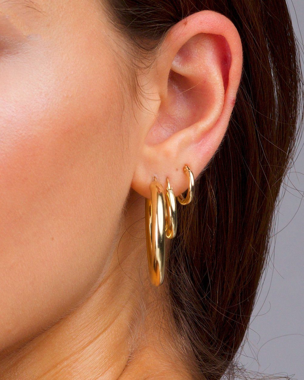 Close-up of dark-haired woman with earring stack in left ear.