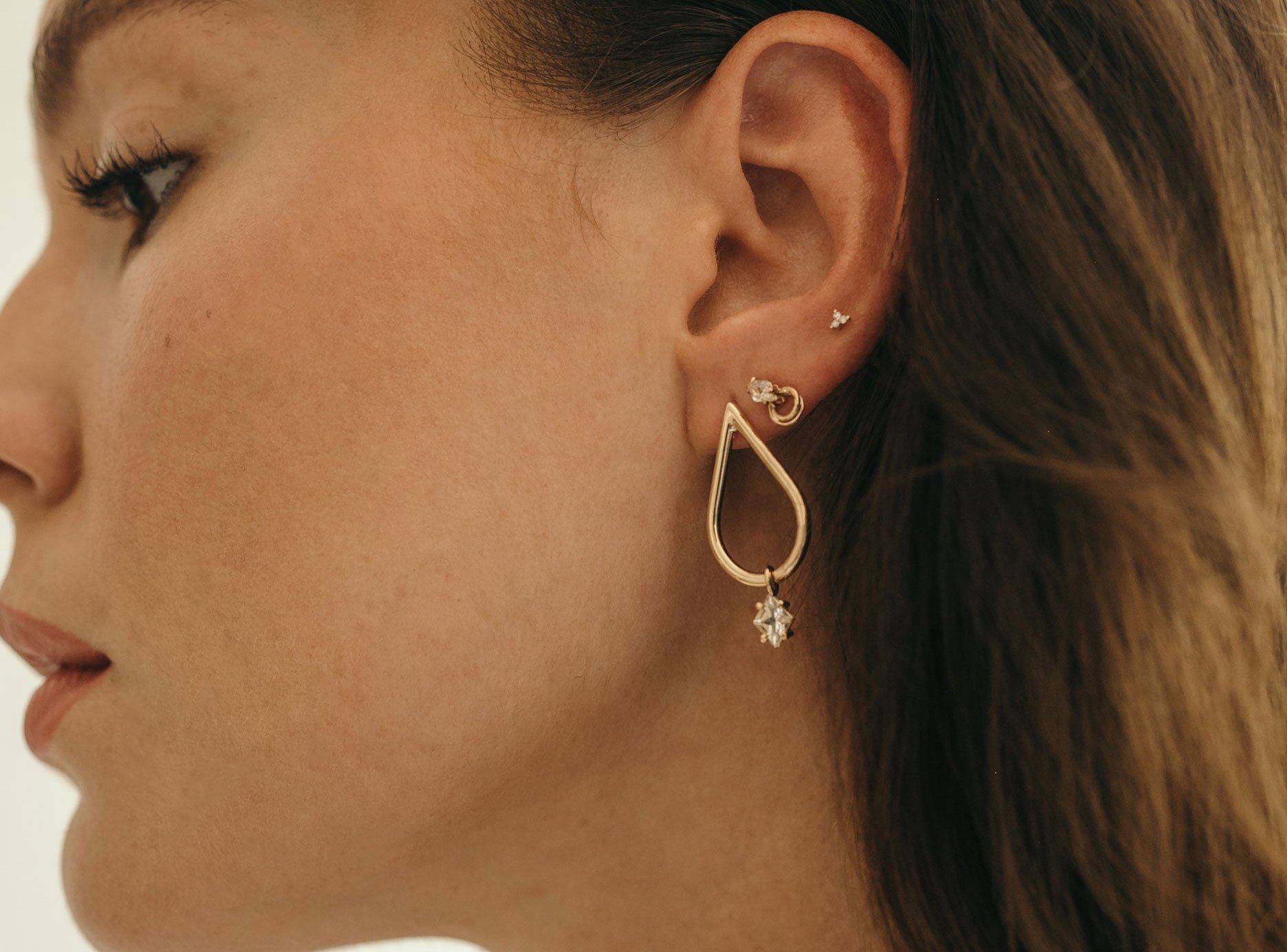 Close-up of dark-haired woman with earring stack in left ear.