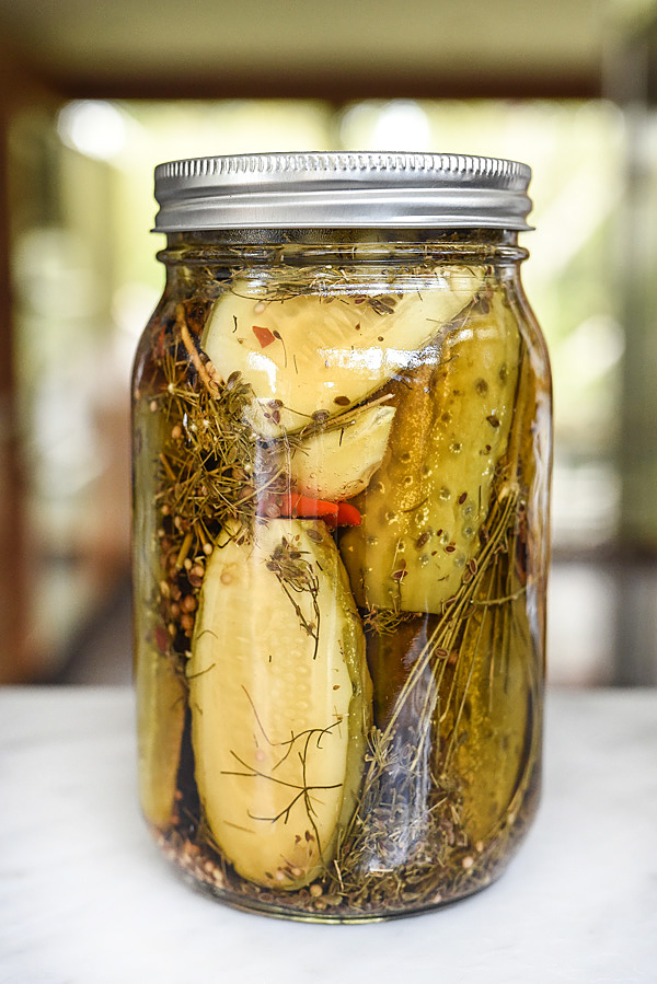 Jar of pickles and herbs sitting on kitchen counter