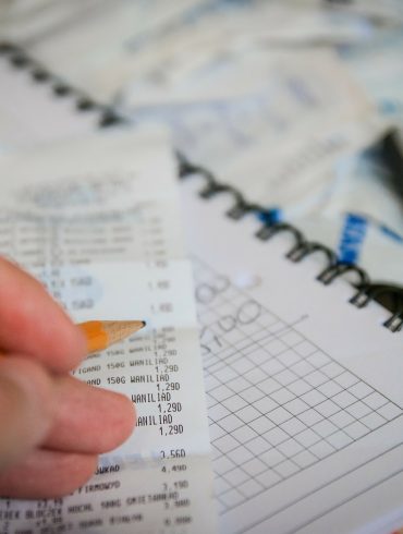 Hand holding pencil over receipts and financial papers